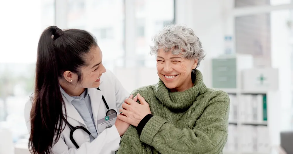 Healthcare provider reassuring an older woman during a medical visit.