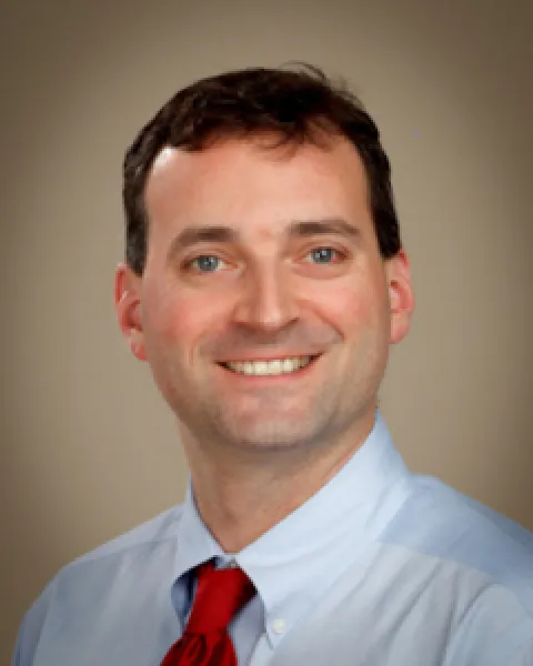 A portrait of Andrew I. Rackoff, MD, smiling in a light blue shirt and red tie against a neutral background.