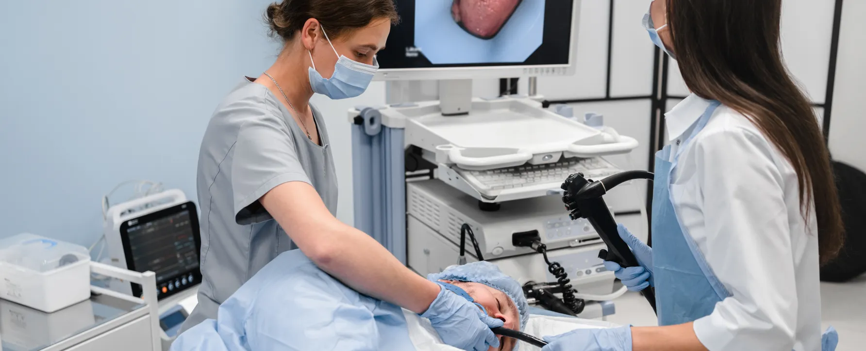 Two healthcare professionals performing an upper endoscopy on a patient."
